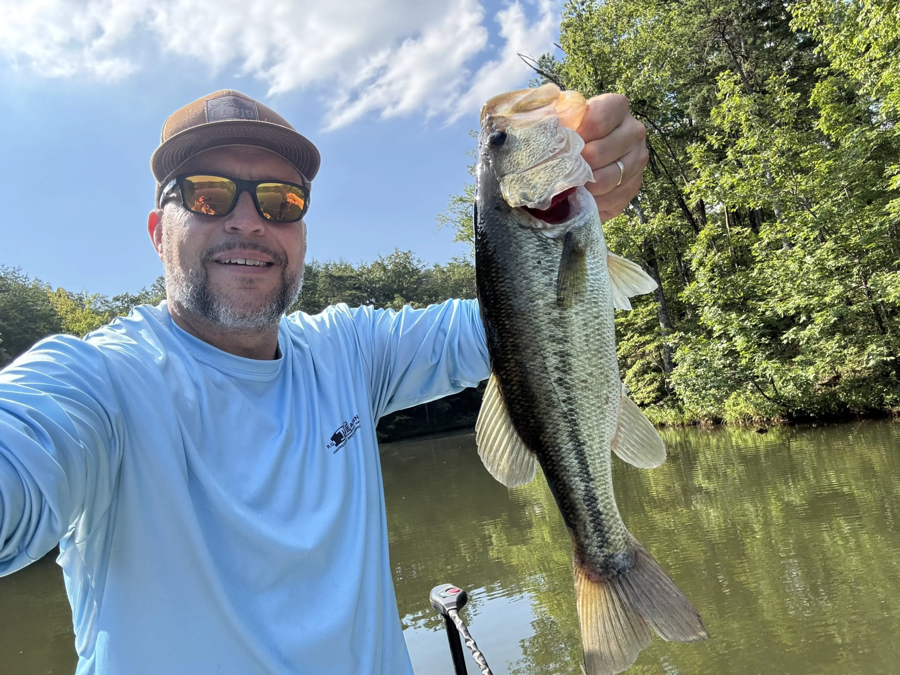 Man holding a fish by the lake.