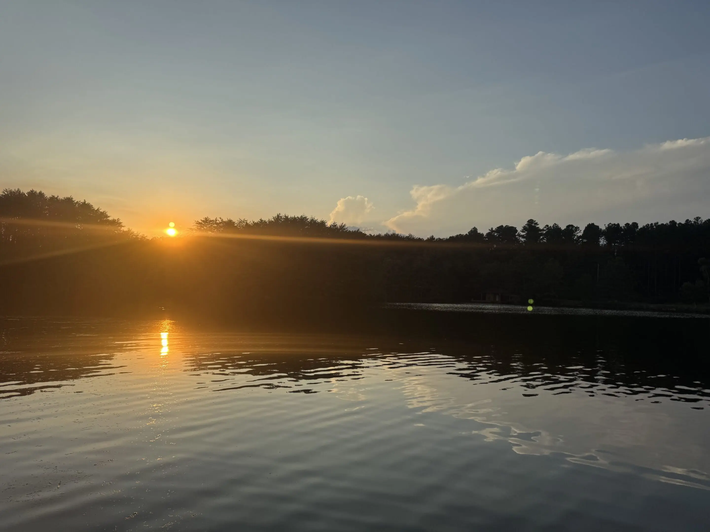 Sunset over calm lake and trees.